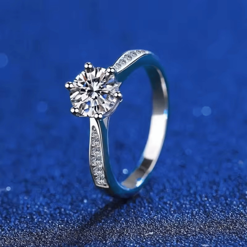 Anel solitário clássico cravejado com Moissanite em prata 925, vista vertical sobre fundo azul