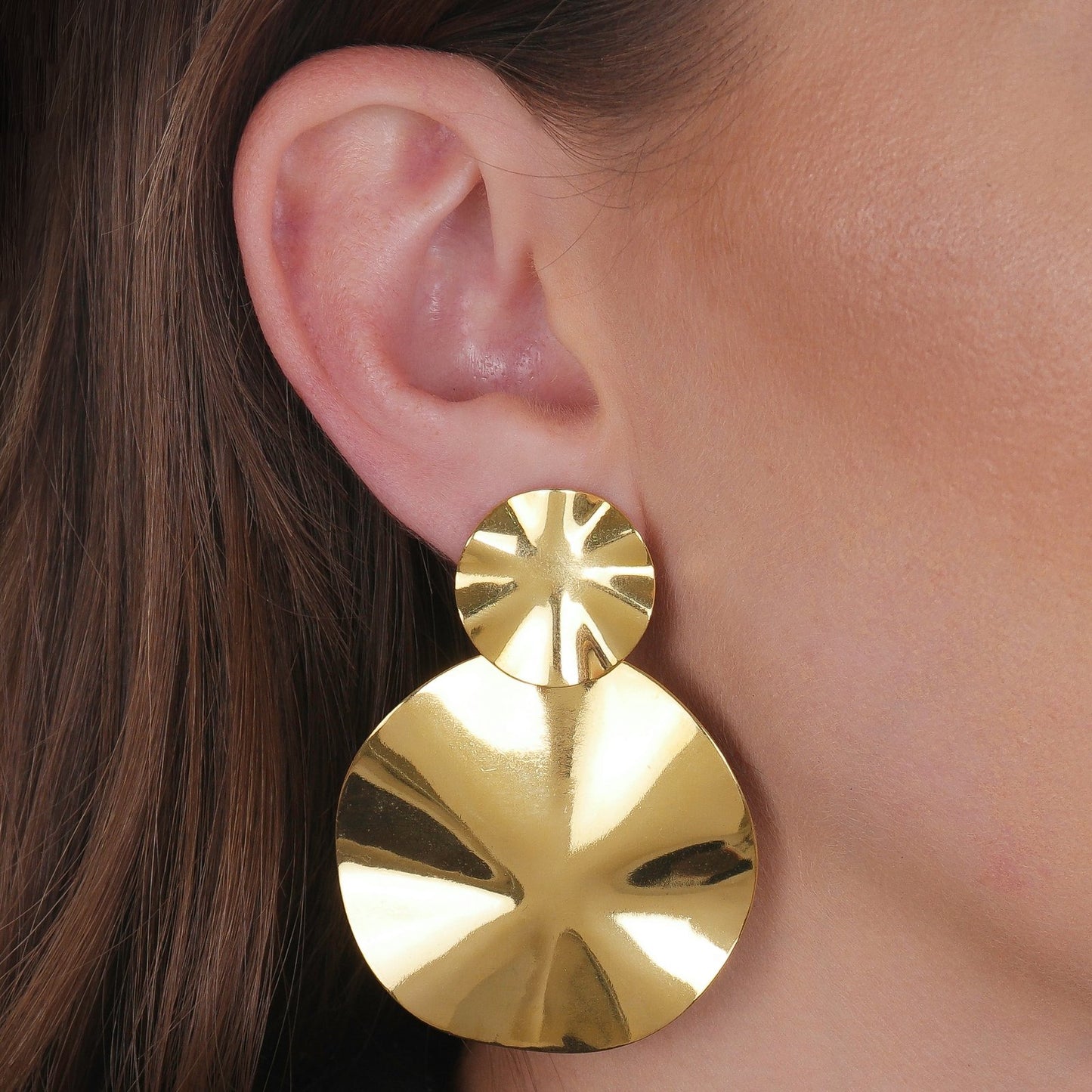 Modelo com Brinco Dourado Orgânico Dois Círculos Amassados em fundo branco