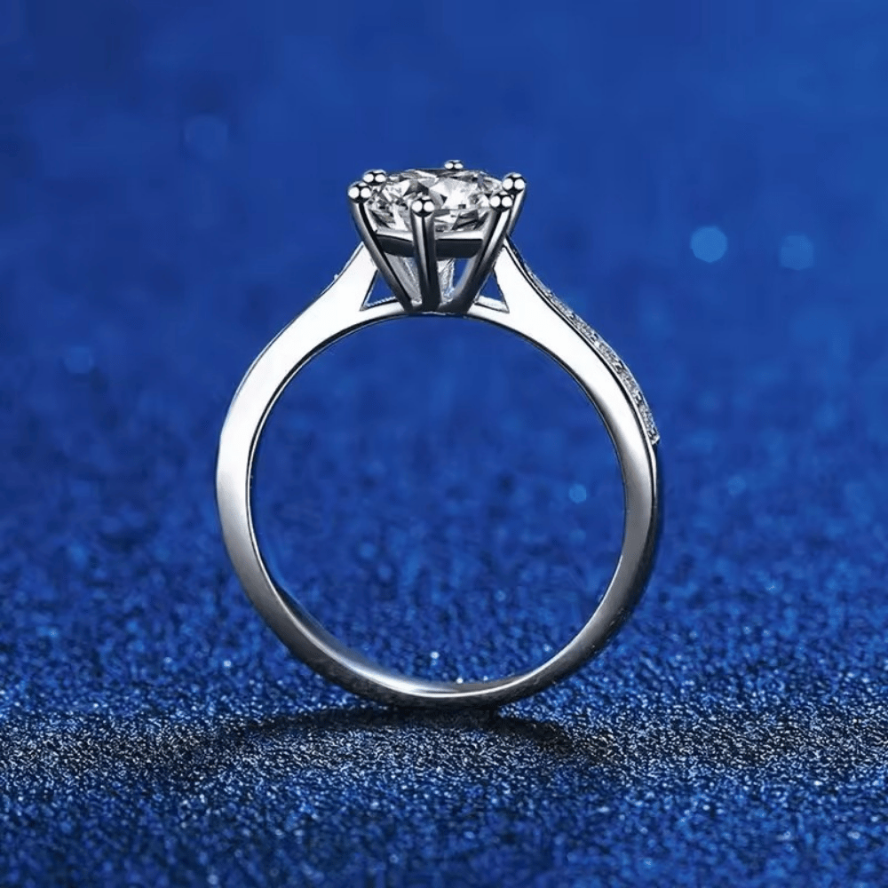 Anel solitário clássico cravejado com Moissanite em prata 925, vista em pé sobre fundo azul