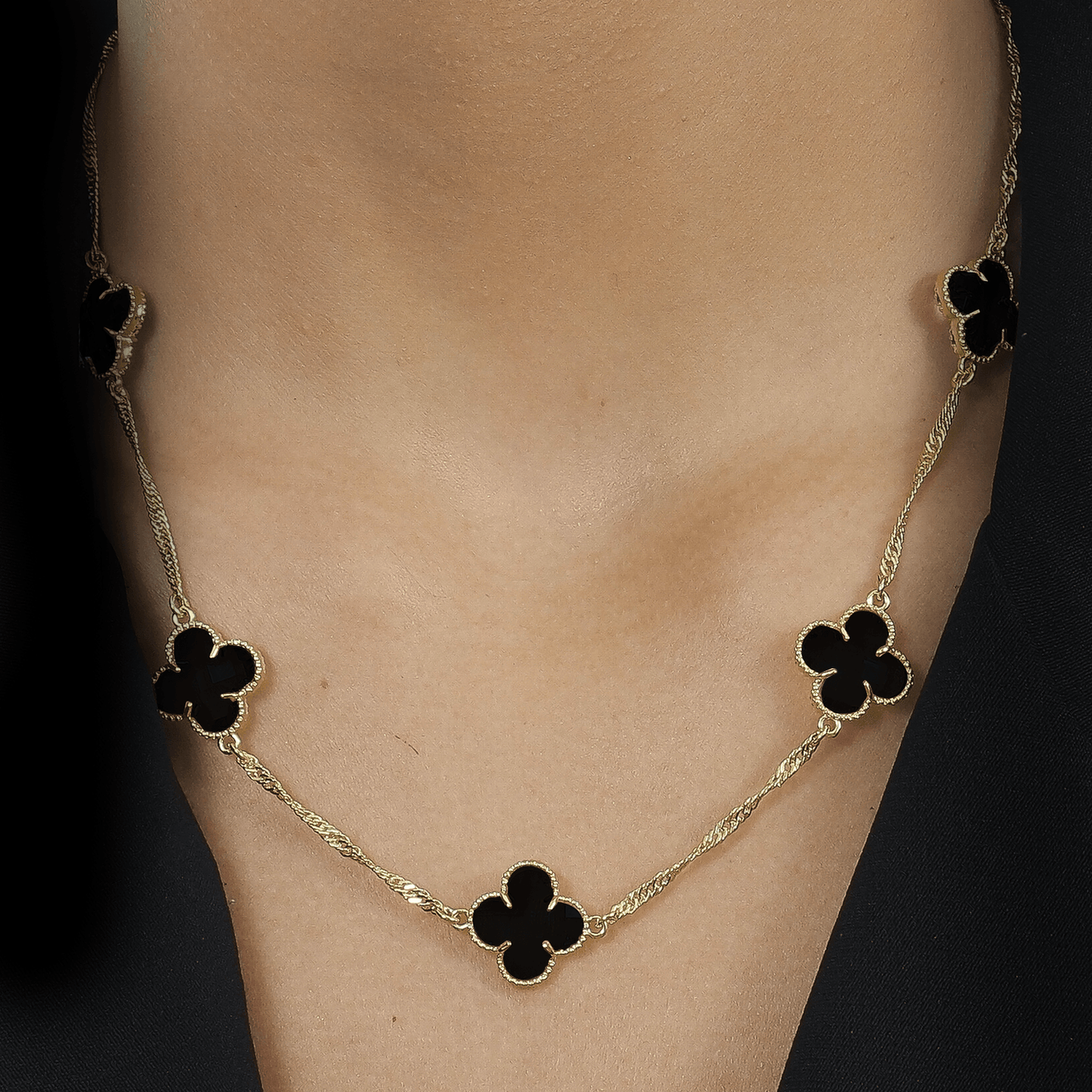 Modelo com Colar dourado Aetheria com cinco trevos e zircônias pretas