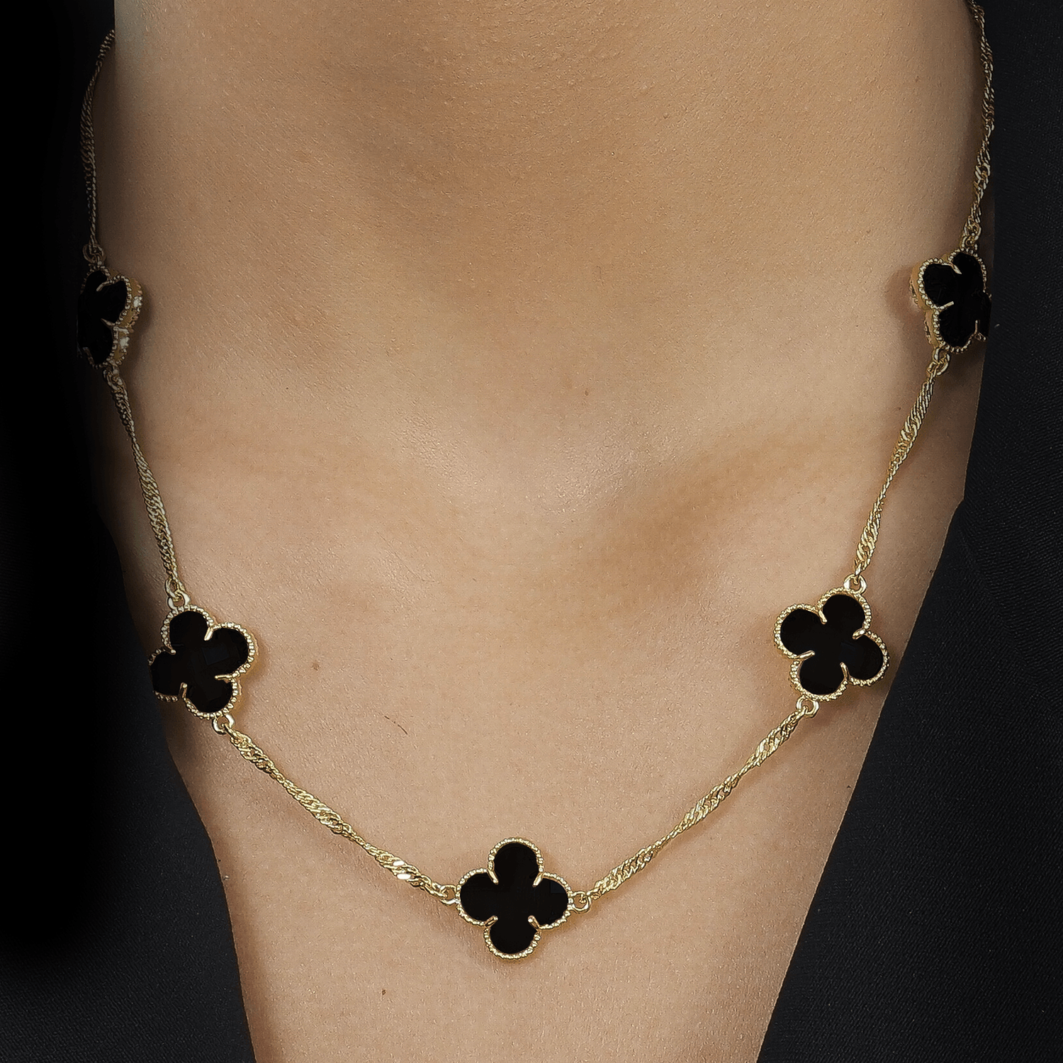 Modelo com Colar dourado Aetheria com cinco trevos e zircônias pretas