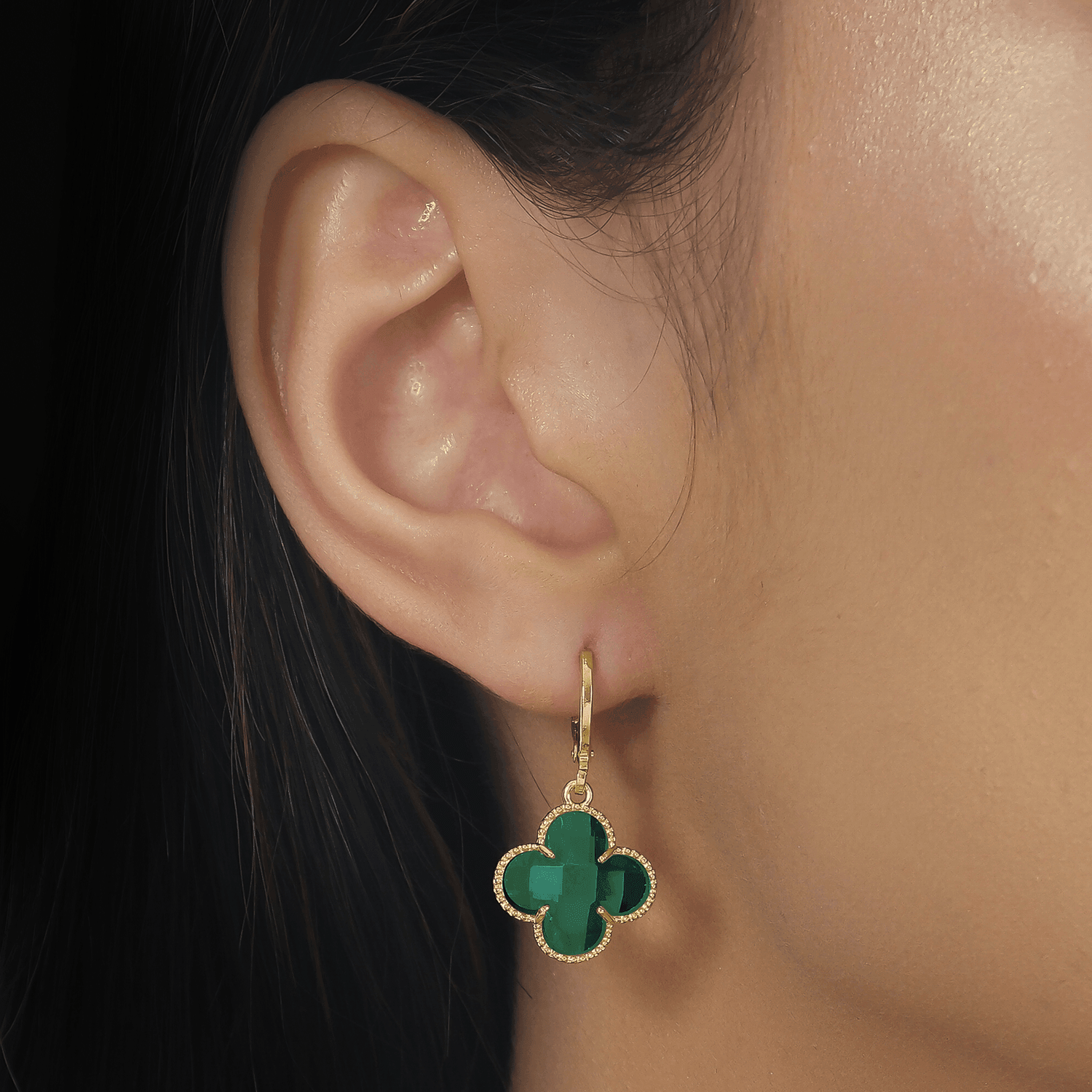 Modelo com Brinco Dourado de Trevos com Zircônia Verde